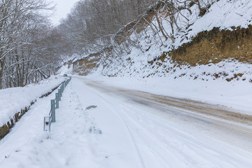 Obraz premium Snow covered road through a forest
