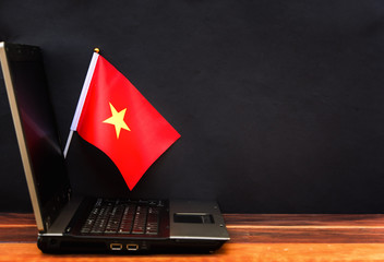  flag of Vietnam , computer, laptop on table and dark background