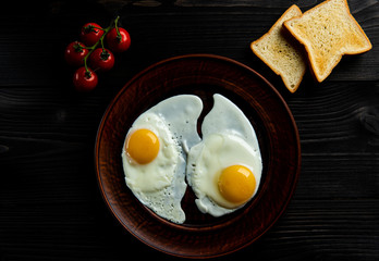breakfast of scrambled eggs with fresh tomatoes and two slices of bread on a dark background.