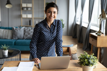 Portrait of smiling Indian girl posing at home workplace
