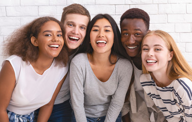 Portrait of happy multiethnic young friends over white wall background