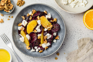 Beetroot salad with feta cheese, oranges and walnuts in a blue bowl. Healthy food. Top view