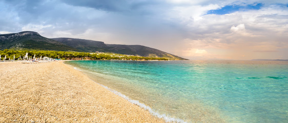 Obraz premium Pebble beach Zlatni Rat or Golden Horn in Bol, Brac Island, Croatia. Scenic gravel beach, mountain and turquoise sea water