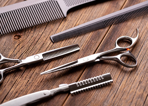 Many tools for cutting hair and beard. Barber tools on a wooden table. Scissors, combs and razor close-up.