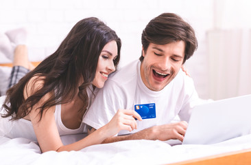 Happy married couple ordering food delivery via laptop