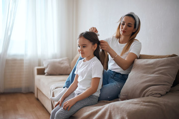 Mommy brushing her little daughter's hair in baedroom, preparing her to a kindergarden, school. close up photo.