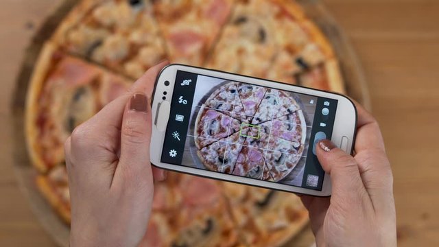 Photographing Pizza Using a Smartphone Cell phone. Close-Up Of Hands Taking Pictures Of Pizza Using A Mobile Phone