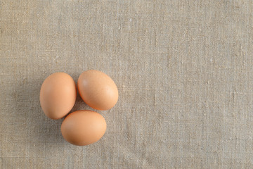Three fresh brown chicken eggs on a canvas background. Healthy good nutrition. Natural organic farm products.