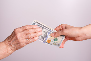 Hand-to-hand transfer of money. Dollars in the hands of an old woman and a young girl.