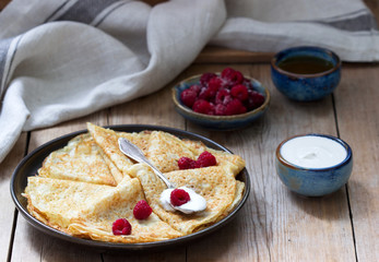 Pancakes served with sour cream, raspberries and honey. The traditional dish on Carnival and Maslenitsa.