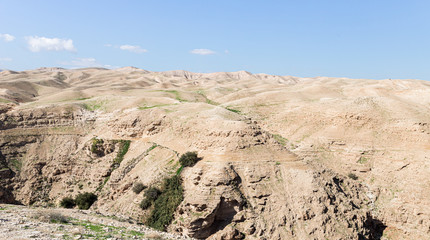 Fototapeta na wymiar Stone Hills of the Judean Desert in the area of the monastery of St. George Hosevit - Mar Jaris - standing near Yeriho in Israel