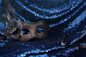 Photo of elegant and delicate black Venetian mask over dark sequins fabric background
