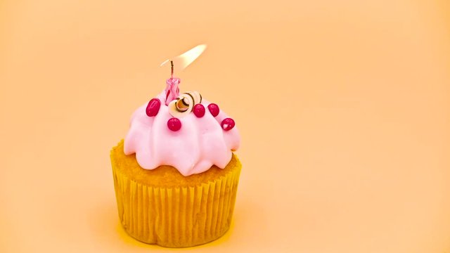 Holiday cake with blowing out candle on orange background .