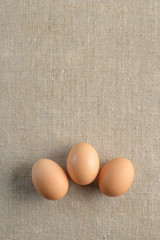 Three fresh brown chicken eggs in row on a canvas background. Healthy good nutrition. Natural organic farm products.