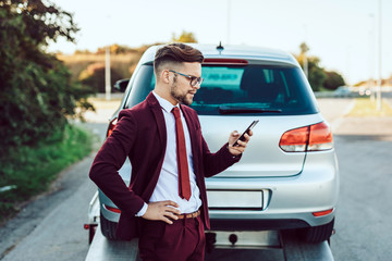 Elegant middle age business man calling towing service for help on the road. Roadside assistance...