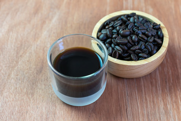 Black coffee cup and roasted coffee beans on wood table.