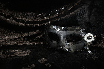 Fototapeta premium Photo of elegant and delicate black Venetian mask over dark sequins fabric background
