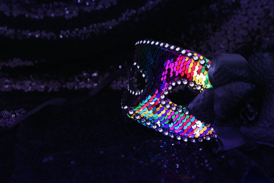 Photo of elegant and delicate colorful sequins Venetian mask over dark fabric background