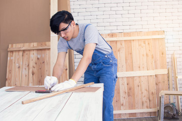 A carpenter is using pencil for marking on wood