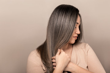 Beautiful plus size model with long colored glossy hair posing on beige studio background