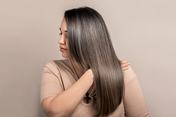 Beautiful plus size model with long colored glossy hair posing on beige studio background