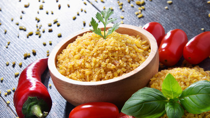 Bowl of uncooked bulgur on wooden table