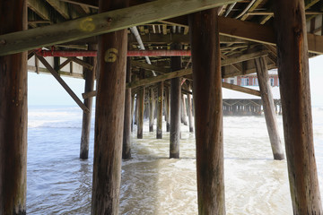 Approaching tide surrounding wooden pier columns