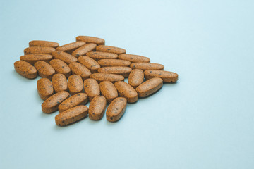 A heap of brown medicine pills on blue surface