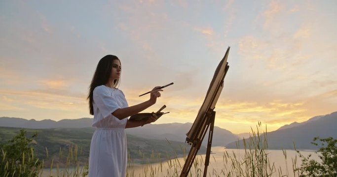 Experienced female artist enjoying her hobby, creating a picture inspired by beautiful landscape - recreational pursuit 4k footage