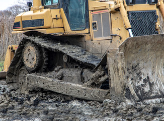 Fototapeta na wymiar Dirty bulldozer standing in the mud. Autumn construction site with working machines.