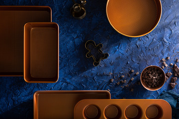 Copper baking sheets with golden scoops and gingerbread molds on a navy blue background