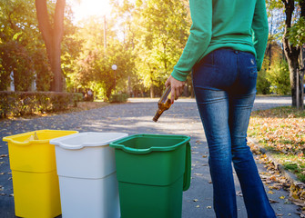 Volunteer girl sorts garbage in the street of the park. Concept of recycling.