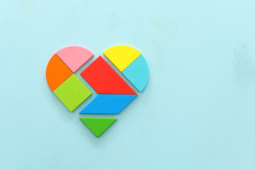 Heart puzzle on blue pastel wooden background