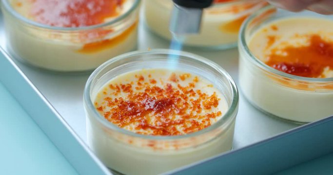Caramelizing sugar on the top of creme brulee dessert using gas torch