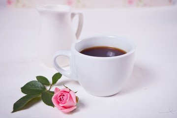 A cup of tea and pink roses on the white table
