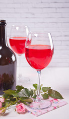Two glasses with red grape wine with bottle and roses on the background. Romantic dinner concept.