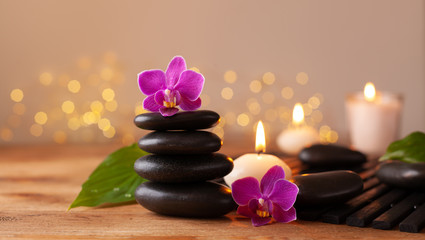 Fototapeta na wymiar Massage stone, orchid flowers and burning candles. Spa and beauty background.