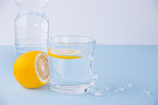 Glass of water, bottle and lemon fruit on the blue table.
