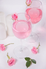 Two glasses with pink grape wine with rose flowers. Romantic dinner concept.