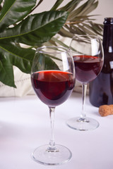 Two glasses with red grape wine with bottle on the background. Romantic dinner concept.