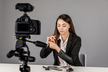 Young blogger in dark suite on grey background.