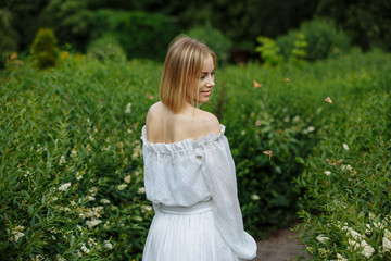 blonde in white dress posing in green