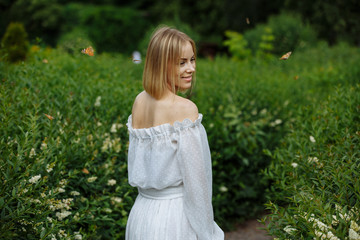 blonde in white dress posing in green