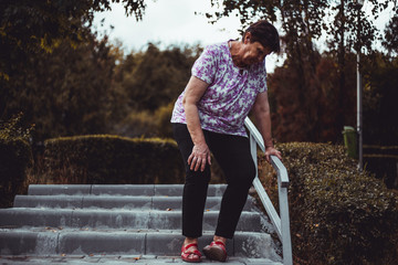 Weak senior woman about to fall on the stairs outside