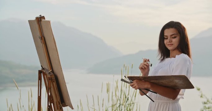 Multiethnic female artist relaxing in mountains, making a picture inspired by beautiul view - recreational pursuit, hobby, inspirational landscape concept 4k footage