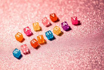 Happy Birthday with colored blocks letters on pink glitter backgrounds. Postcard to celebrate.