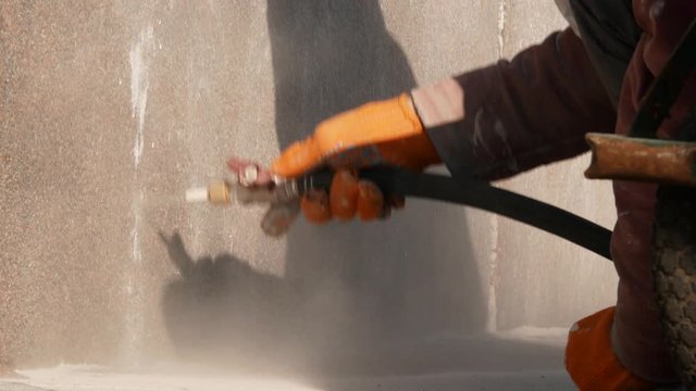 Worker removing graffiti with high pressure cleaner splashing. Cleaning wall using sandblaster gun. Professional cleaning services. Close up 4k
