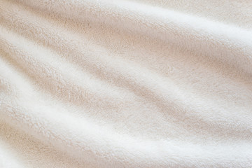 A soft cozy plaid made of white fabric with a pile lies in beautiful folds