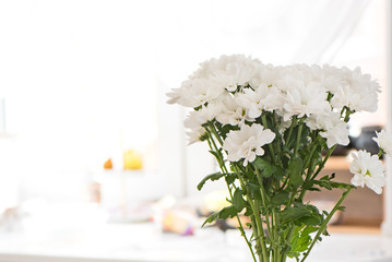 Bouquet of white chrysanthemums close-up on blurred background inside the home environment. Copy space