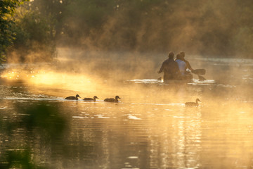 M&auml;nner auf einem ruhigen Gew&auml;sser im Morgengrauen im Kanu